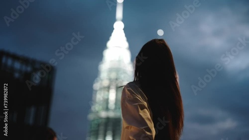 Woman captures video on her phone at night with a smile against a backdrop of glowing skyscrapers, nightlife and freelance tourist