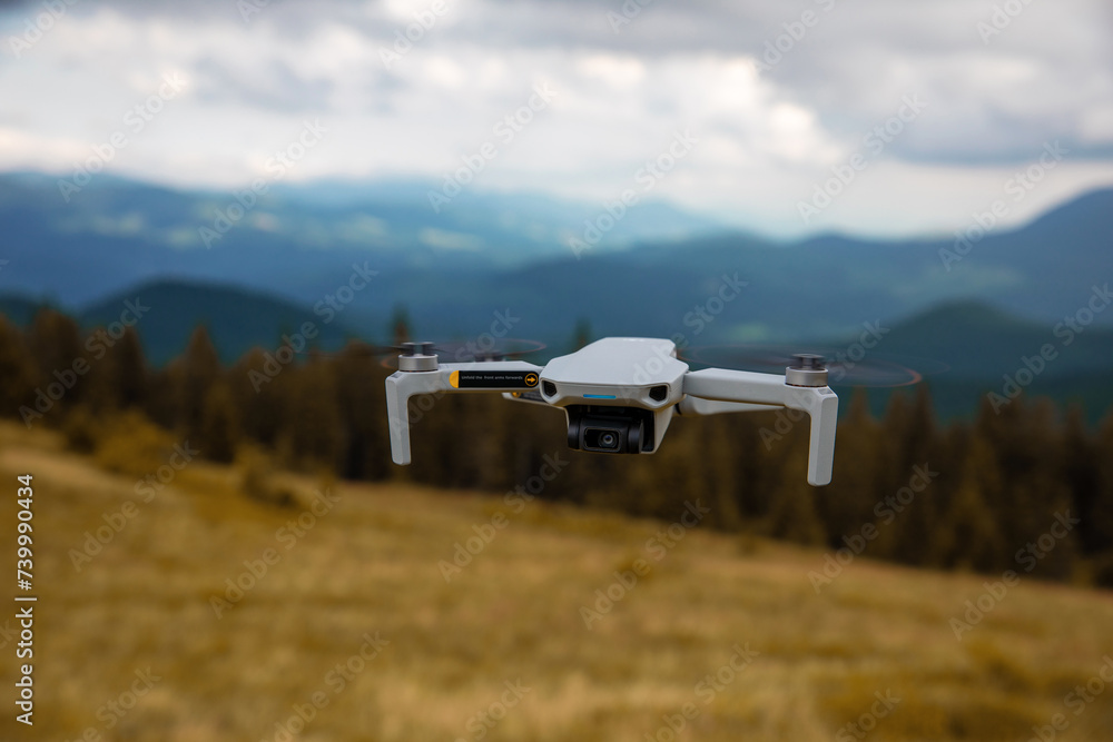 Drone Hovering Above Vast Mountain Terrain Against Clear Blue Sky