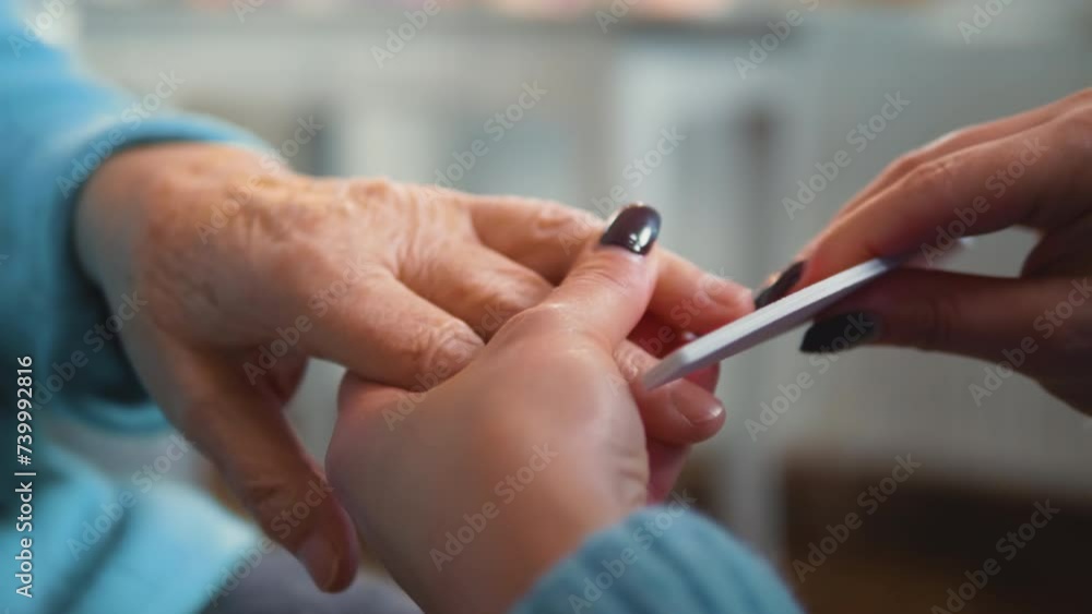 Close up hand of senior grandmother having a manicure, filing nails. Elderly woman is getting a manicure in a beauty salon. Close up hand of senior grandmother having a manicure, filing nails. Elderly woman is getting a manicure in a beauty salon.