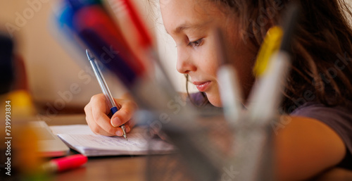 Side view of a focused little boy who is learning to write while doing his homework while sitting at his desk at home. Portrait of a smart preschooler who is learning to write. writing training. photo