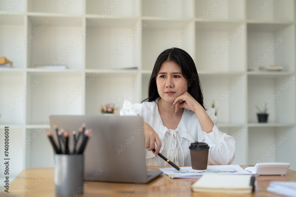 Young businesswoman stressed and having headache while working at desk with laptop in modern office Young businesswoman stressed and having headache while working at desk with laptop in modern office
