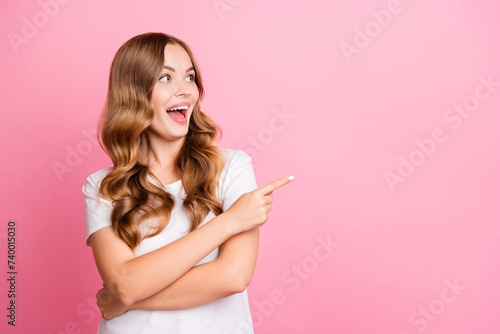 Photo of impressed woman with wavy hair dressed white t-shirt directing look at crazy sale empty space isolated on pink color background