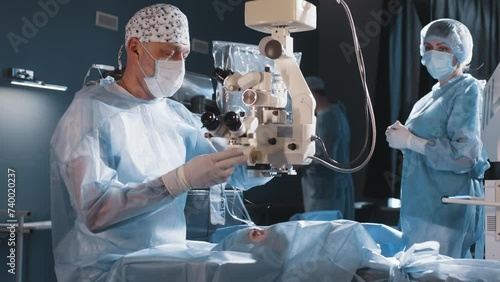 A surgeon looks through a microscope at a patient's eyes in the operating room. The doctor uses a microscope during eye surgery or diagnostics, cataract treatment and diopter correction. photo