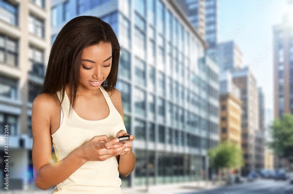 Happy young woman standing on street holding phone Happy young woman standing on street holding phone