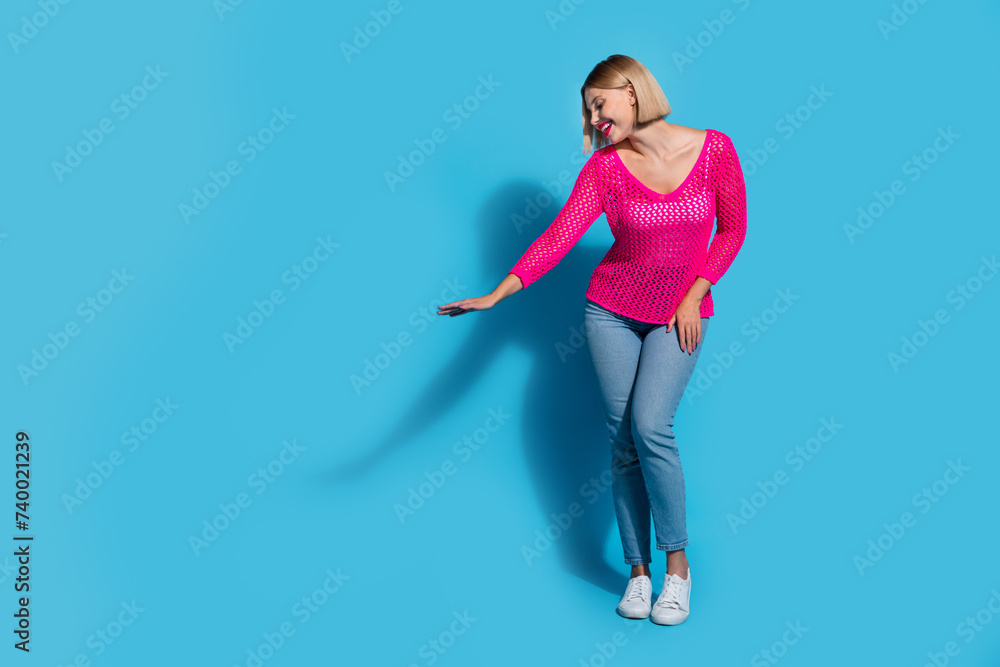Full size photo of pretty young girl palm show measure empty space wear trendy pink knitted outfit isolated on blue color background Full size photo of pretty young girl palm show measure empty space wear trendy pink knitted outfit isolated on blue color background
