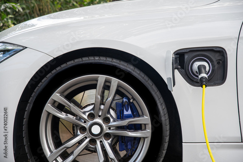 The white color electric vehicle plugged the cable for charging