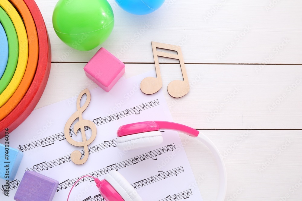 Notes, music sheet, headphones and toys on white wooden table, flat lay with space for text. Baby song concept Notes, music sheet, headphones and toys on white wooden table, flat lay with space for text. Baby song concept
