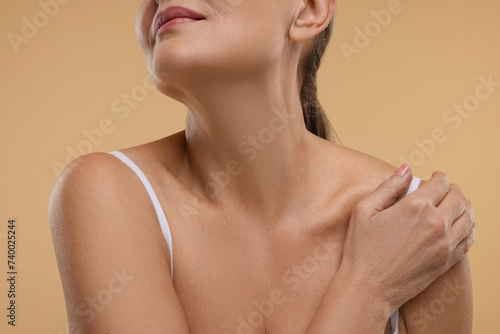 Mature woman with healthy skin on beige background, closeup