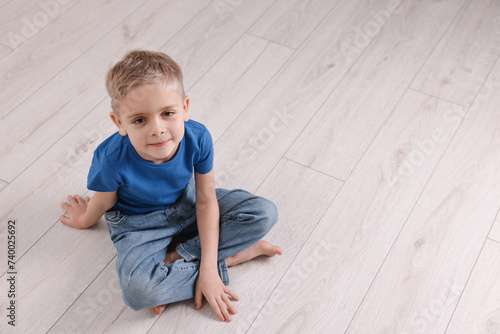 Cute little boy sitting on warm floor indoors, space for text. Heating system