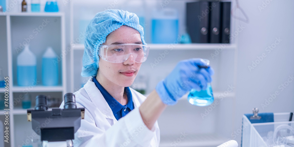 © Supapich - Closeup female woman scientist's hand holding blue liquid chemical chemistry test tube flask working in analyze science laboratory research experiment