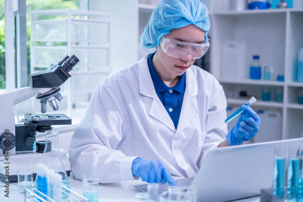 Closeup female woman scientist's hand holding blue liquid chemical chemistry test tube working in analyze science laboratory research experiment Closeup female woman scientist's hand holding blue liquid chemical chemistry test tube working in analyze science laboratory research experiment