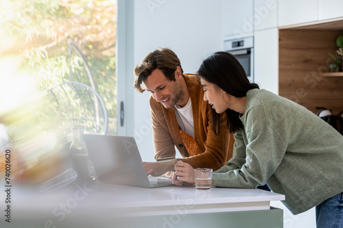 Adult couple using laptop together at kitchen counter