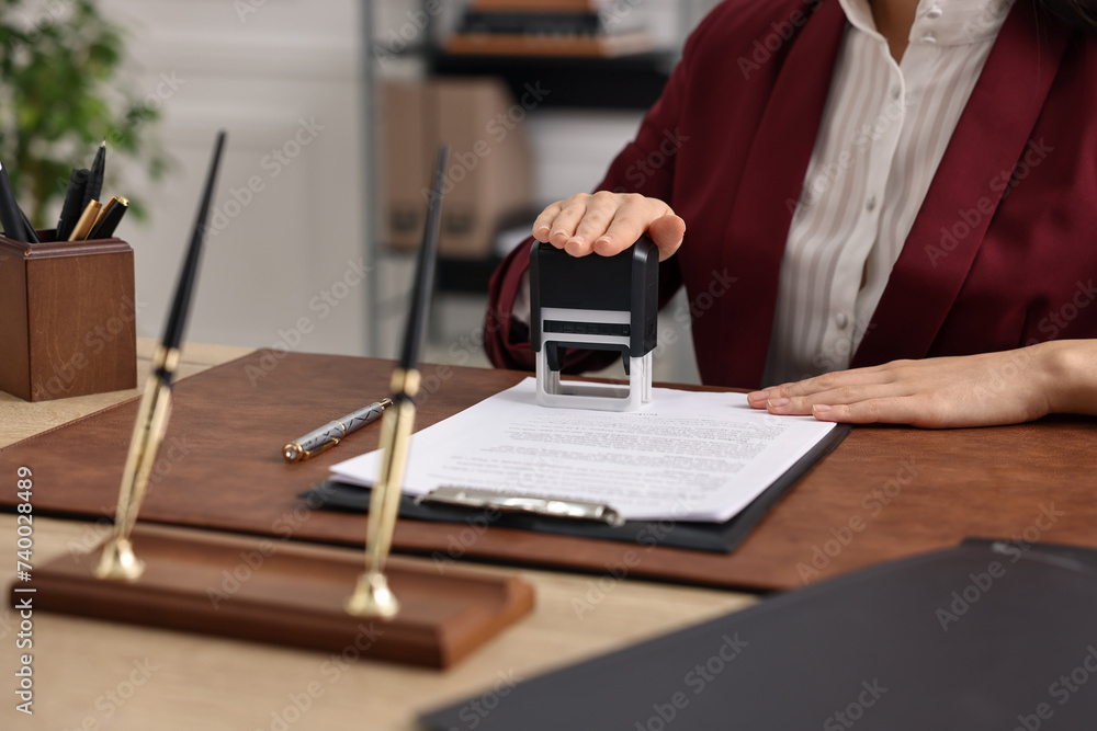 Notary stamping document at table in office, closeup Notary stamping document at table in office, closeup