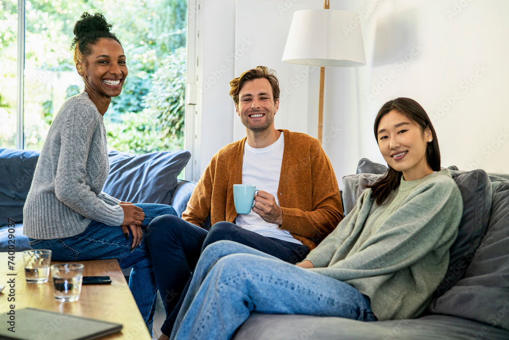 Small group of friends gathered in living room looking at the camera Small group of friends gathered in living room looking at the camera