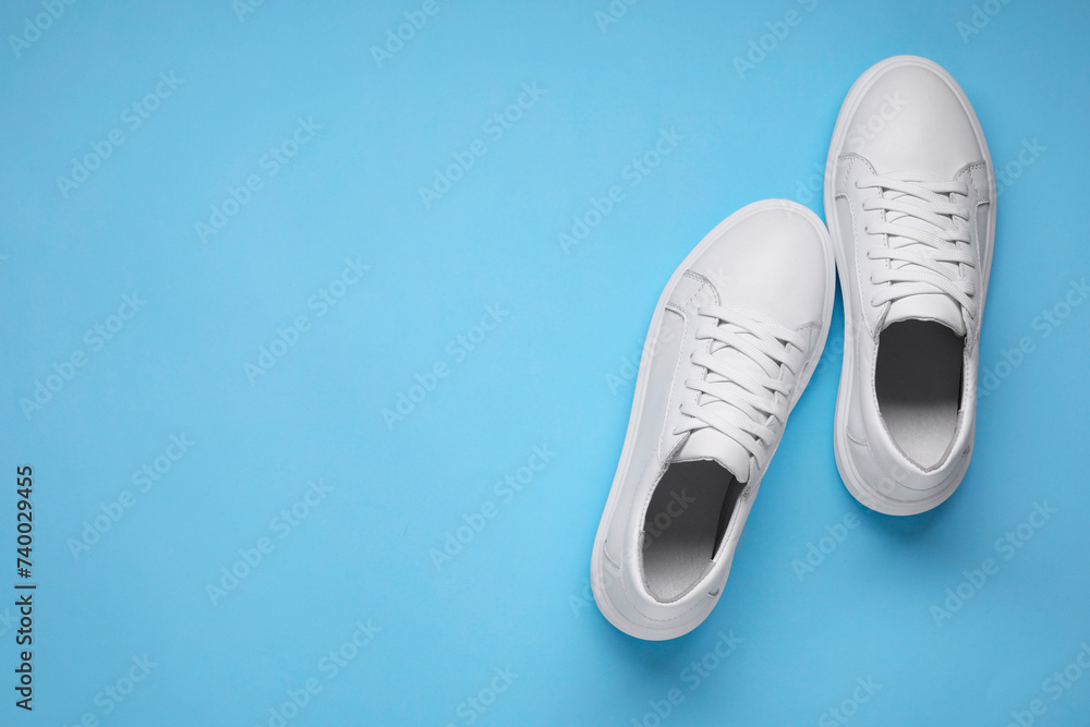 Pair of stylish white sneakers on light blue background, top view. Space for text Pair of stylish white sneakers on light blue background, top view. Space for text
