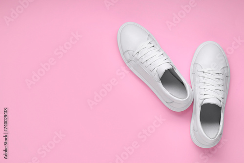 Pair of stylish white sneakers on pink background, top view. Space for text