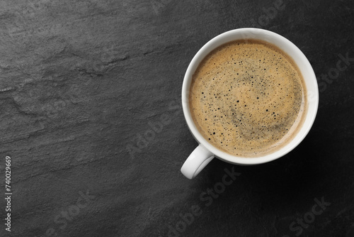 Cup of aromatic coffee on black table, top view. Space for text