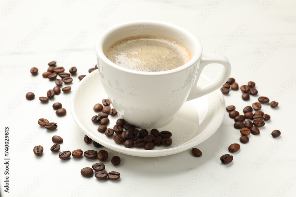 Cup of aromatic coffee and beans on white table, closeup Cup of aromatic coffee and beans on white table, closeup