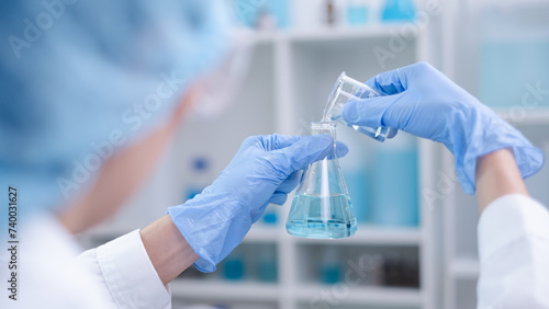 Foto Close-up hands holding pouring blue fluid liquid beaker flask test tube glasswar