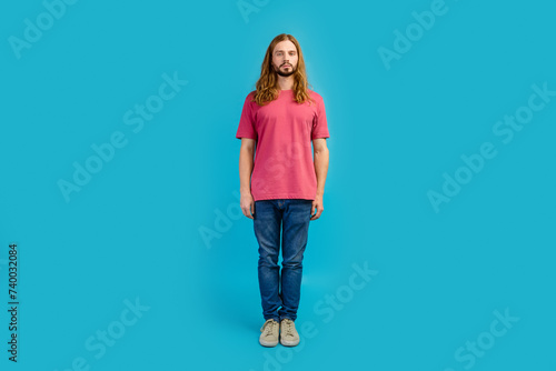 Full size photo of calm focused concentrated young man standing posing isolated on blue color background