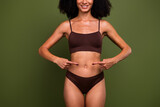 Cropped no filter photo of smiling happy girl showing her tummy healthy diet slimming isolated on khaki color background