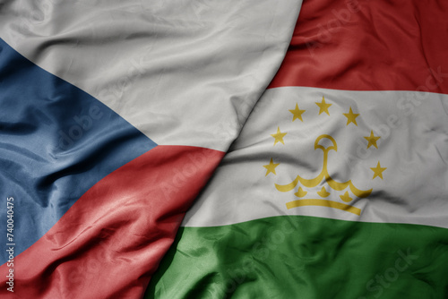 big waving national colorful flag of tajikistan and national flag of czech republic.
