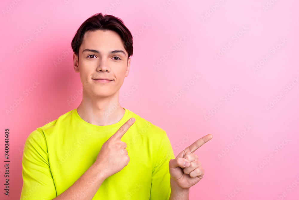 Photo portrait of nice teen man point empty space poster dressed stylish yellow clothes isolated on pink color background Photo portrait of nice teen man point empty space poster dressed stylish yellow clothes isolated on pink color background