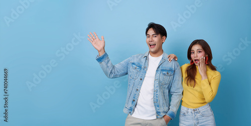 Happy Asian teen couple presenting or showing open hand palm with for product isolated on blue studio copy space background.