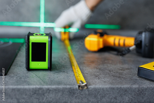 Close-up of hands of a worker who measures the width of a tabletop with a tape measure and a laser.