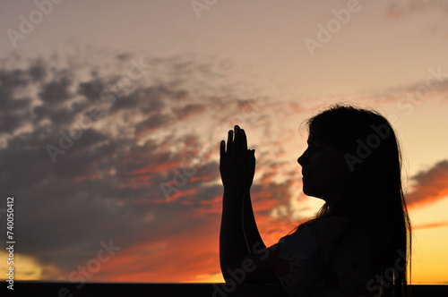 garota criança feliz com mãos elevadas em agradecimento e oração, silhueta em lindo pôr do sol