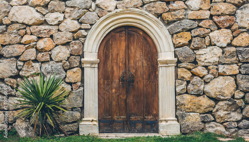 old wooden door with a carved arch in the stone wall; beautiful vintage background