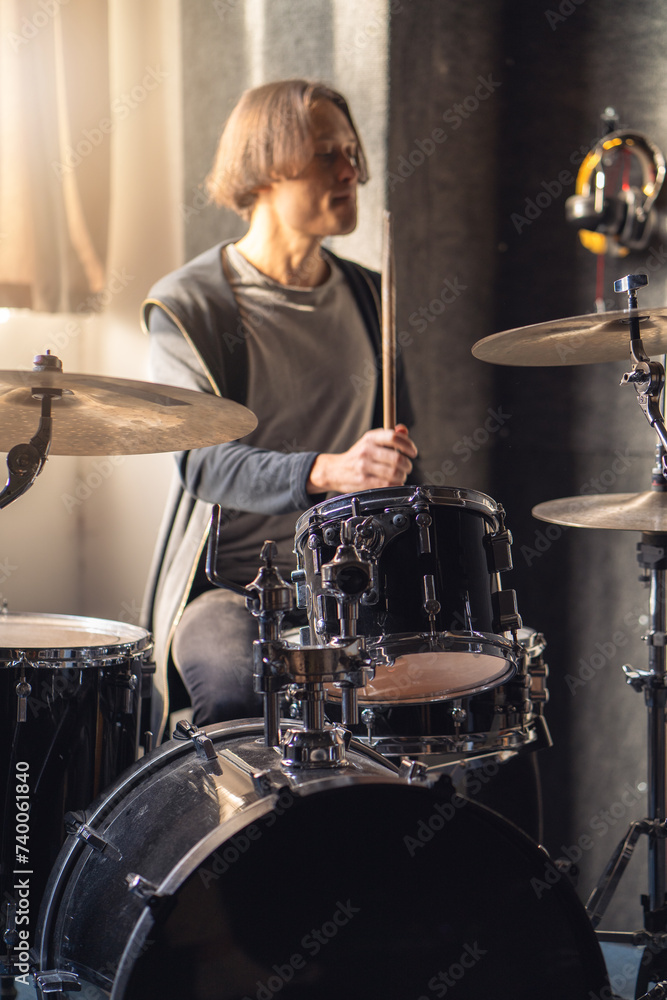 Fototapeta premium Drummer is playing musical instrument drum, with drumhead and cymbal in sound recording studio.