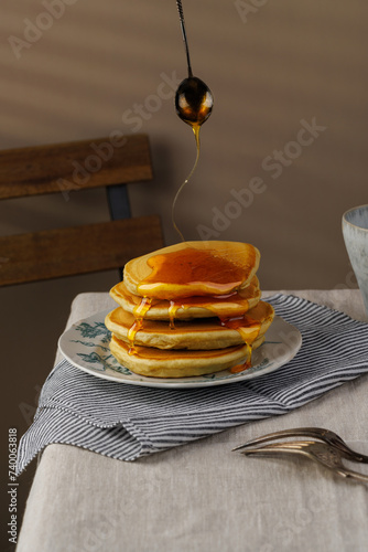 A stack of pancakes with honey on a vintage plate on the table. Breakfast. (ID: 740063818)