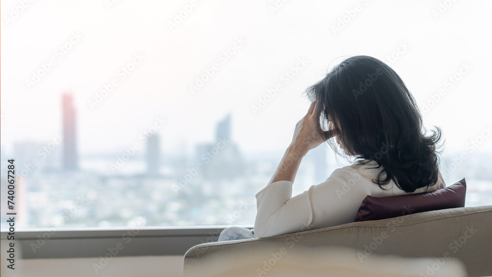 Fototapeta premium Anxiety disorder menopause woman with mental health illness, stressful depressed aging businesswoman female person with panic attack, headache and migraine sitting at home with city background