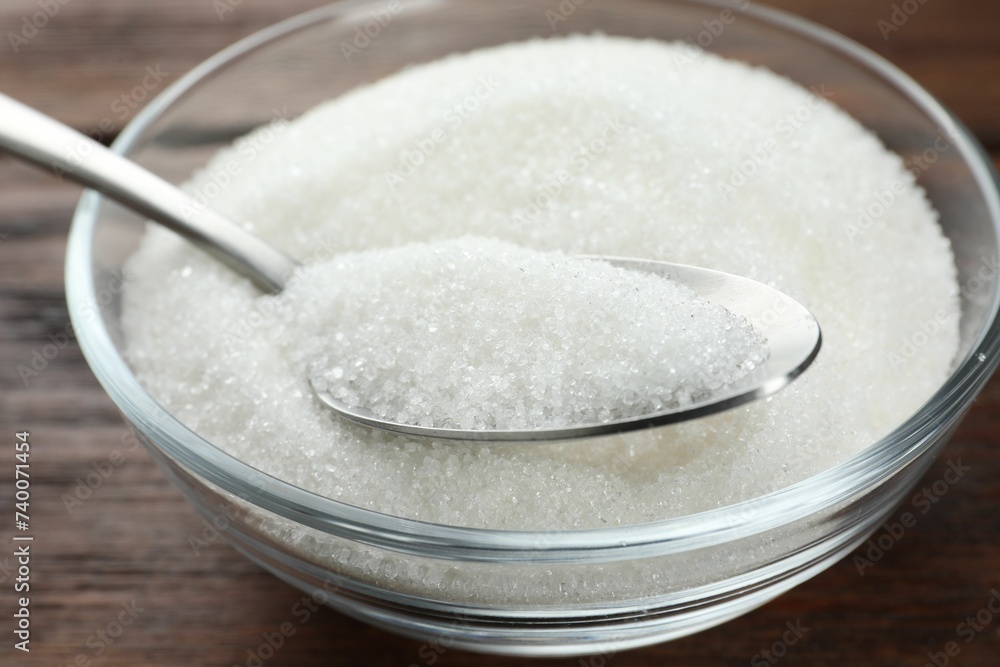 Granulated sugar in bowl and spoon on wooden table, closeup Granulated sugar in bowl and spoon on wooden table, closeup