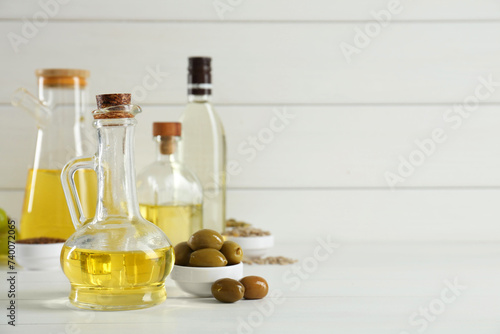 Vegetable fats. Different cooking oils in bottles and ingredients on white wooden table, space for text