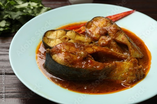 Tasty fish curry on wooden table, closeup. Indian cuisine