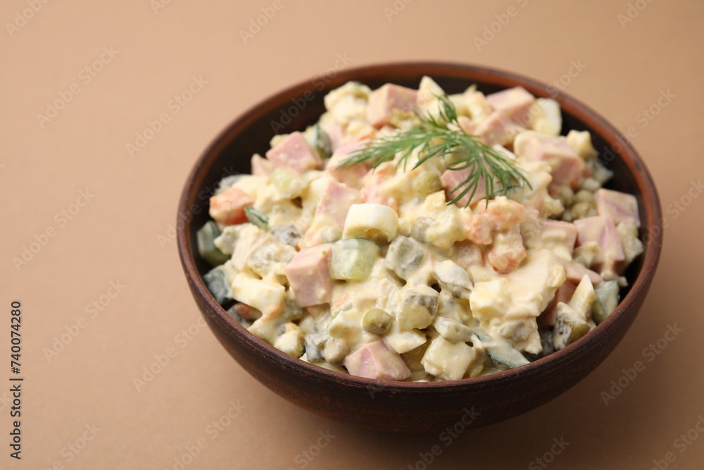 Tasty Olivier salad with boiled sausage in bowl on beige table Tasty Olivier salad with boiled sausage in bowl on beige table
