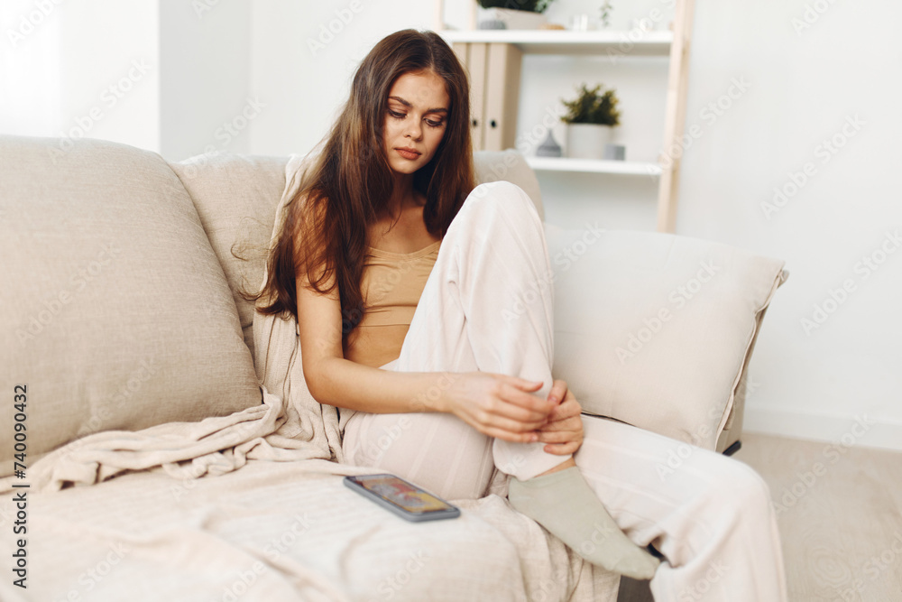Relaxed Woman Holding Mobile Phone on Cozy Sofa, Enjoying Online Games and Chatting in Living Room Relaxed Woman Holding Mobile Phone on Cozy Sofa, Enjoying Online Games and Chatting in Living Room