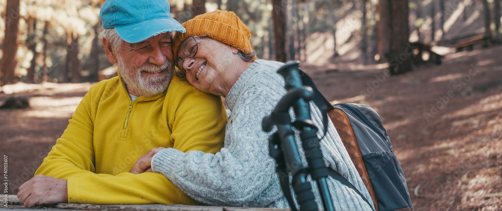 Head shot portrait close up of cute couple of old middle age people having fun and enjoying together in the forest of the mountain at the table relaxing and resting. Mature woman hugging husband love