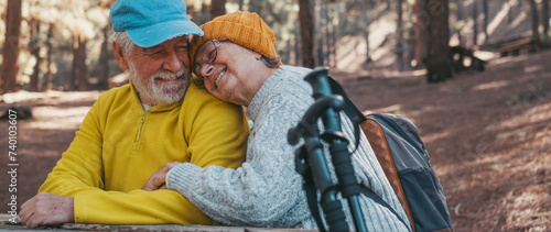 Head shot portrait close up of cute couple of old middle age people having fun and enjoying together in the forest of the mountain at the table relaxing and resting. Mature woman hugging husband love