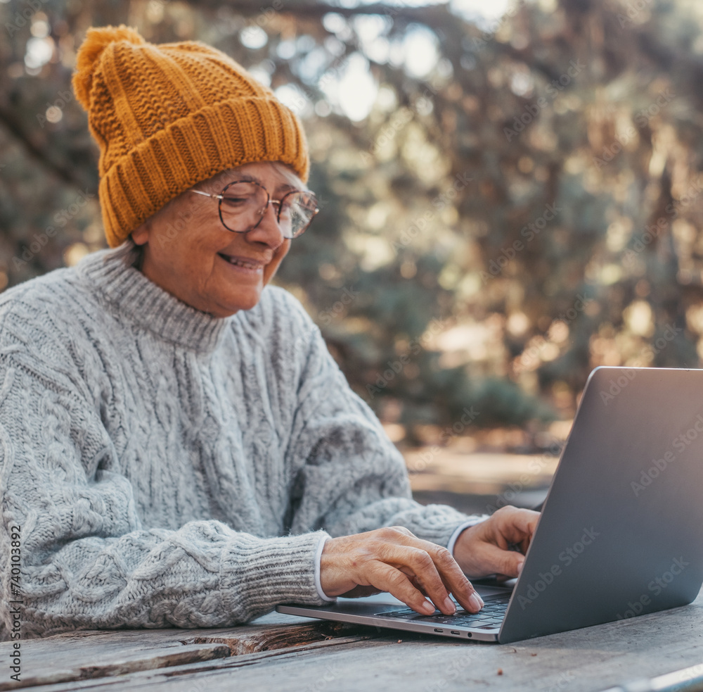 Head shot portrait close up of cute one of old middle age person using computer pc outdoors sitting at a wooden table in the forest of mountain in nature with trees around her.. Head shot portrait close up of cute one of old middle age person using computer pc outdoors sitting at a wooden table in the forest of mountain in nature with trees around her..