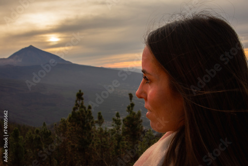 Face of a woman in profile looking towards the teide volcano at sunset.