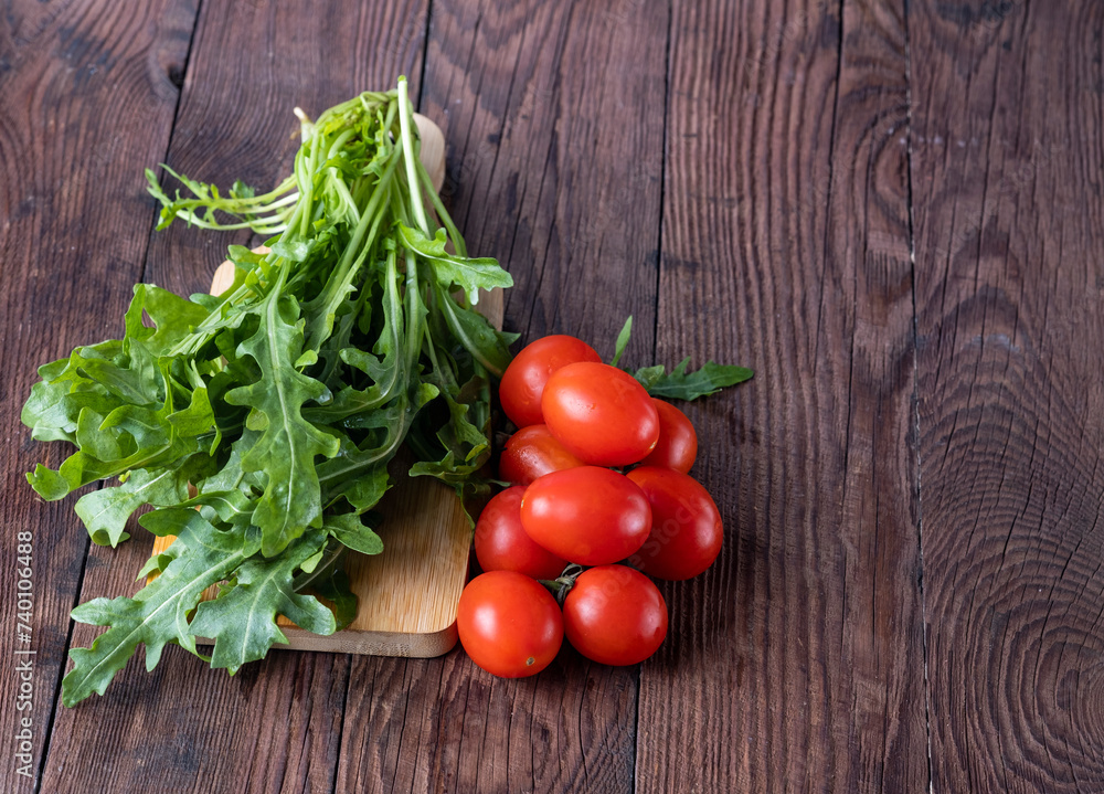 Fresh arugula and cherry tomatoes on a wooden table. Fresh arugula and cherry tomatoes on a wooden table.