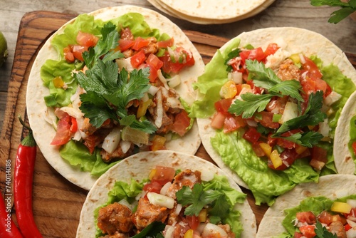 Delicious tacos with vegetables and meat on wooden table  flat lay