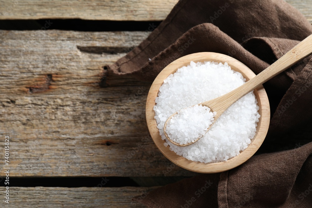Organic salt in bowl and spoon on wooden table, top view. Space for text Organic salt in bowl and spoon on wooden table, top view. Space for text