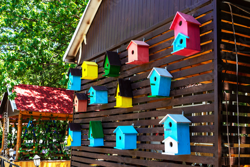 Colorful creative wooden nesting boxes birdhouse hanged on a wall in backyard photo
