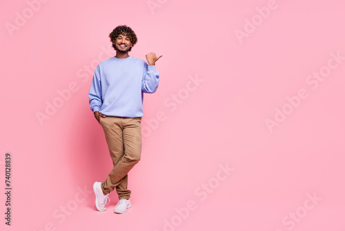 Full length photo of handsome young male point empty space promo wear trendy blue garment isolated on pink color background