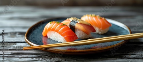 A plate filled with delicious sushi rolls, accompanied by a pair of chopsticks, placed on a rustic wooden table.