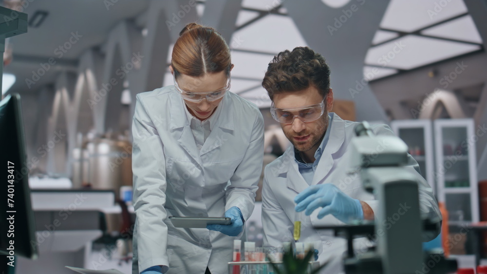 Obraz premium Lab workers experimenting samples looking at computer data in clinic close up
